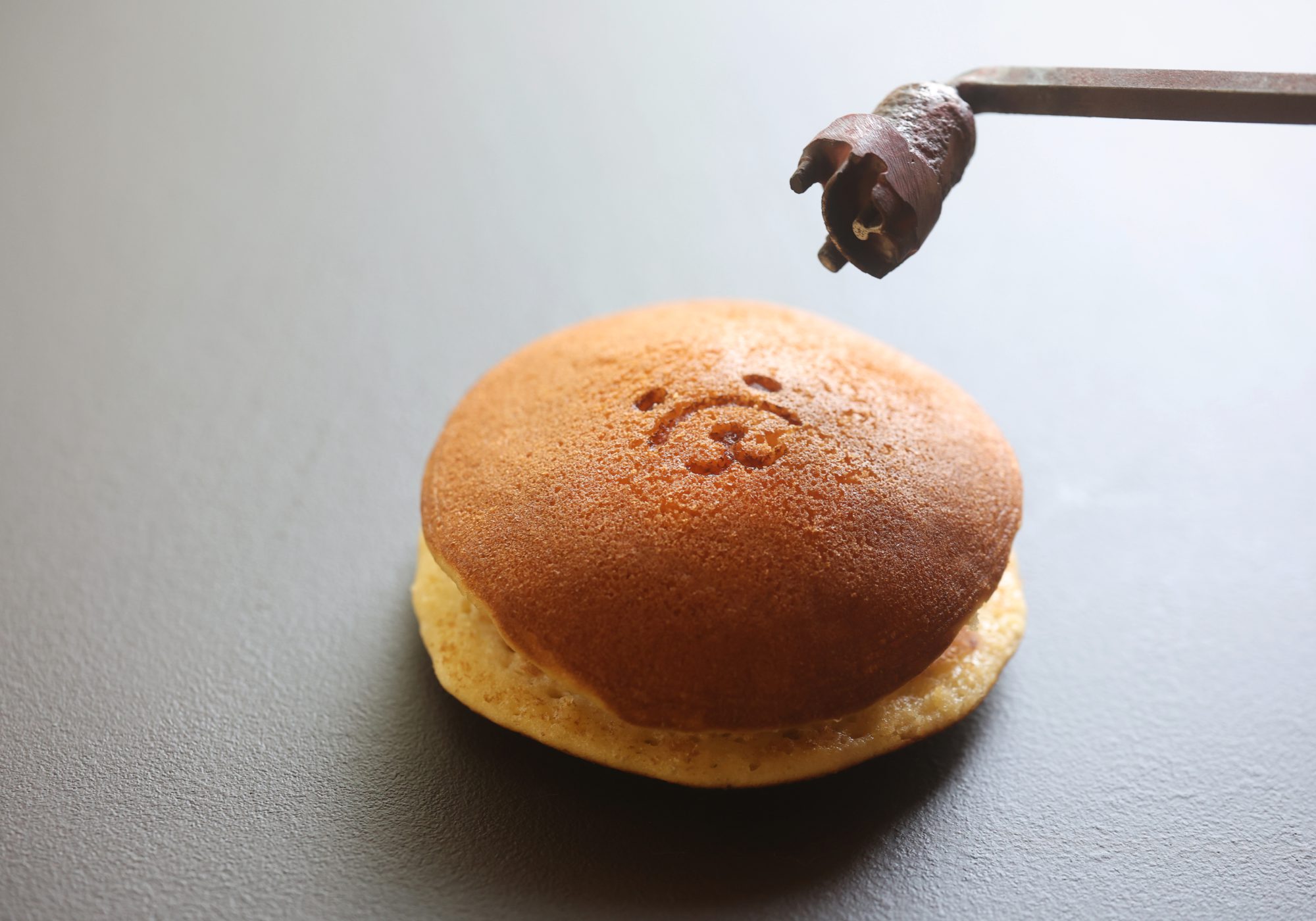 箸で持ち上げた、焼印入りのどら焼き